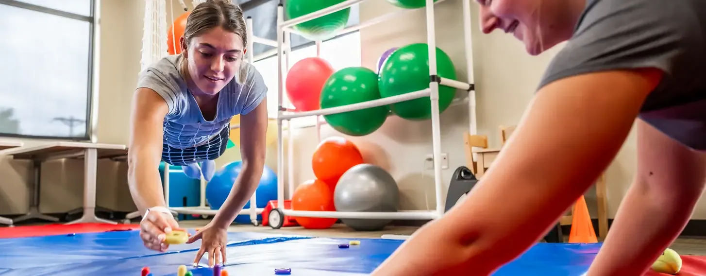 Two students participating in a sensory and motor skills assessment in an occupational therapy classroom.